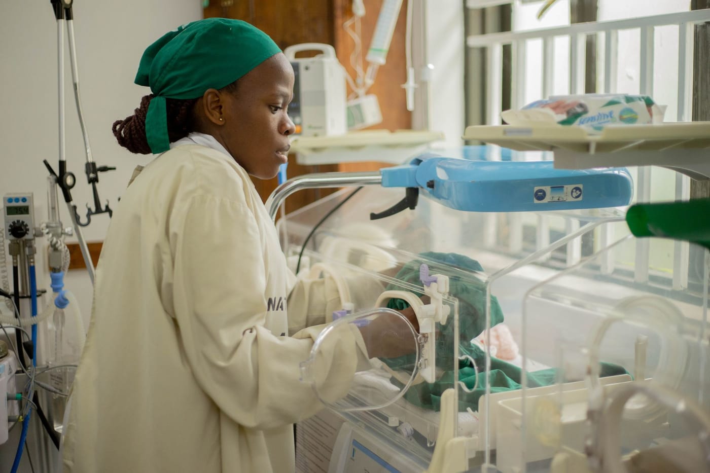 A nurse tends to a newborn in an incubator on a neonatal ward
