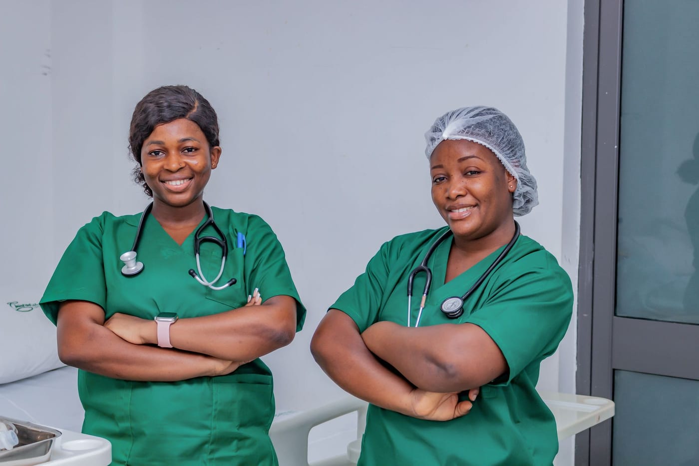 Two nurses in green scrubs sharing a smile on a hospital ward